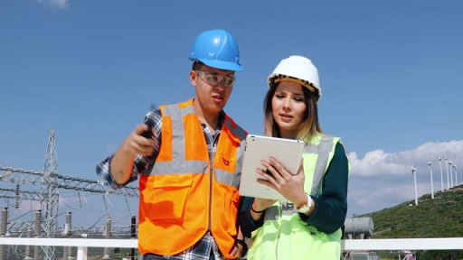 Utility engineers working, checking farm field system and looking up verify at wind turbine - a connected workforce creates a more agile and safer working environment 